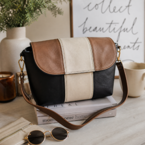 Neutral faux leather Charlotte crossbody bag styled in a warm modern lifestyle setting with gold hardware and color block flap design.