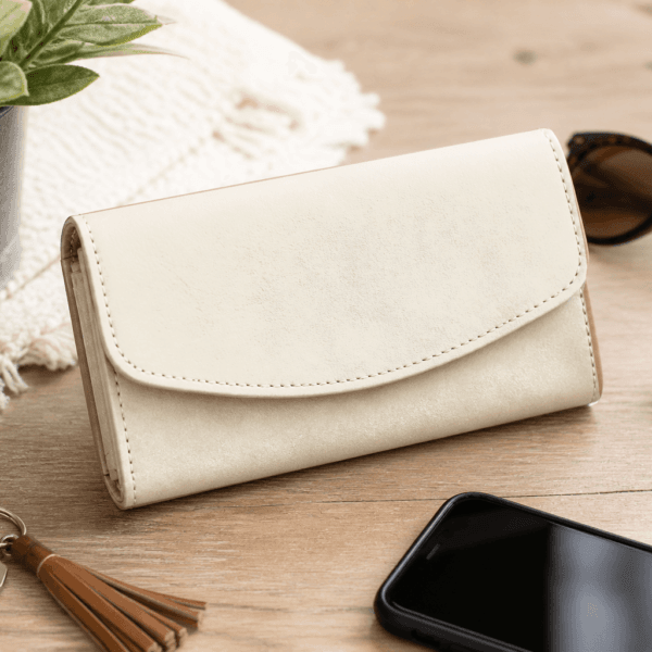Neutral ivory Necessary Clutch Wallet styled on a wooden tabletop with sunglasses, keys, and everyday accessories.