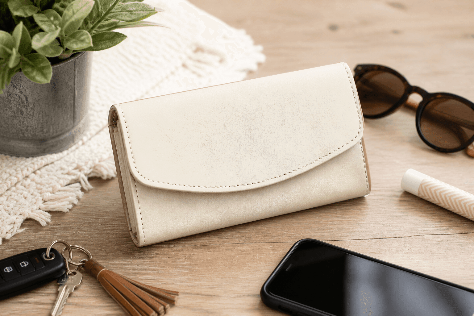 Neutral ivory Necessary Clutch Wallet styled on a wooden tabletop with sunglasses, keys, and everyday accessories.