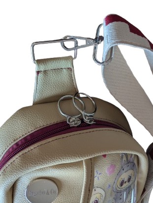 beige character sling bag top view zipper and strap hardware detail