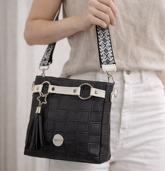 black faux leather crossbody handbag worn on model adjustable strap