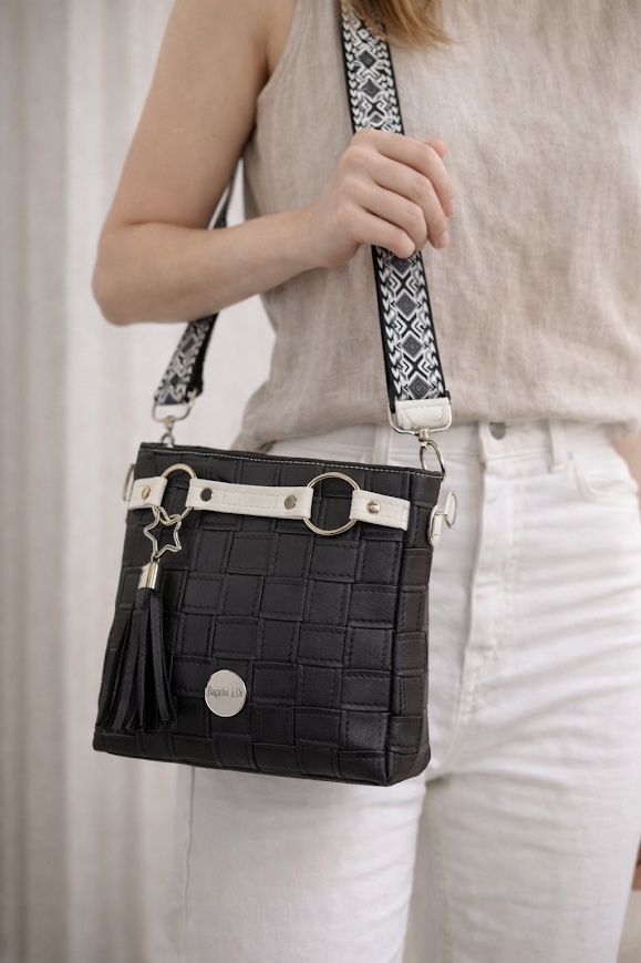 black faux leather crossbody handbag worn on model adjustable strap