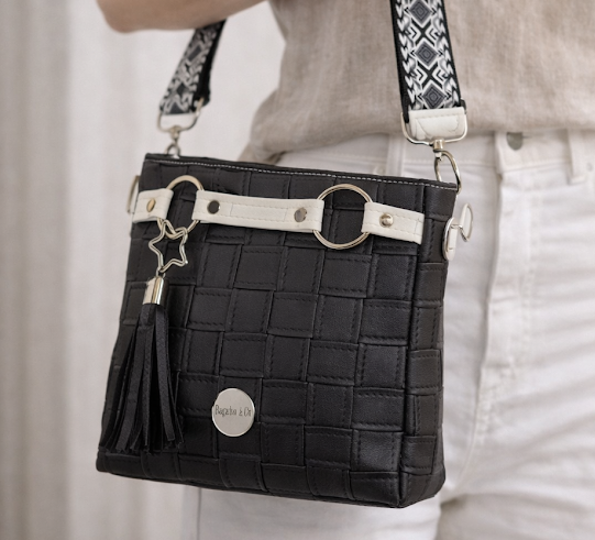black faux leather crossbody handbag worn on model adjustable strap