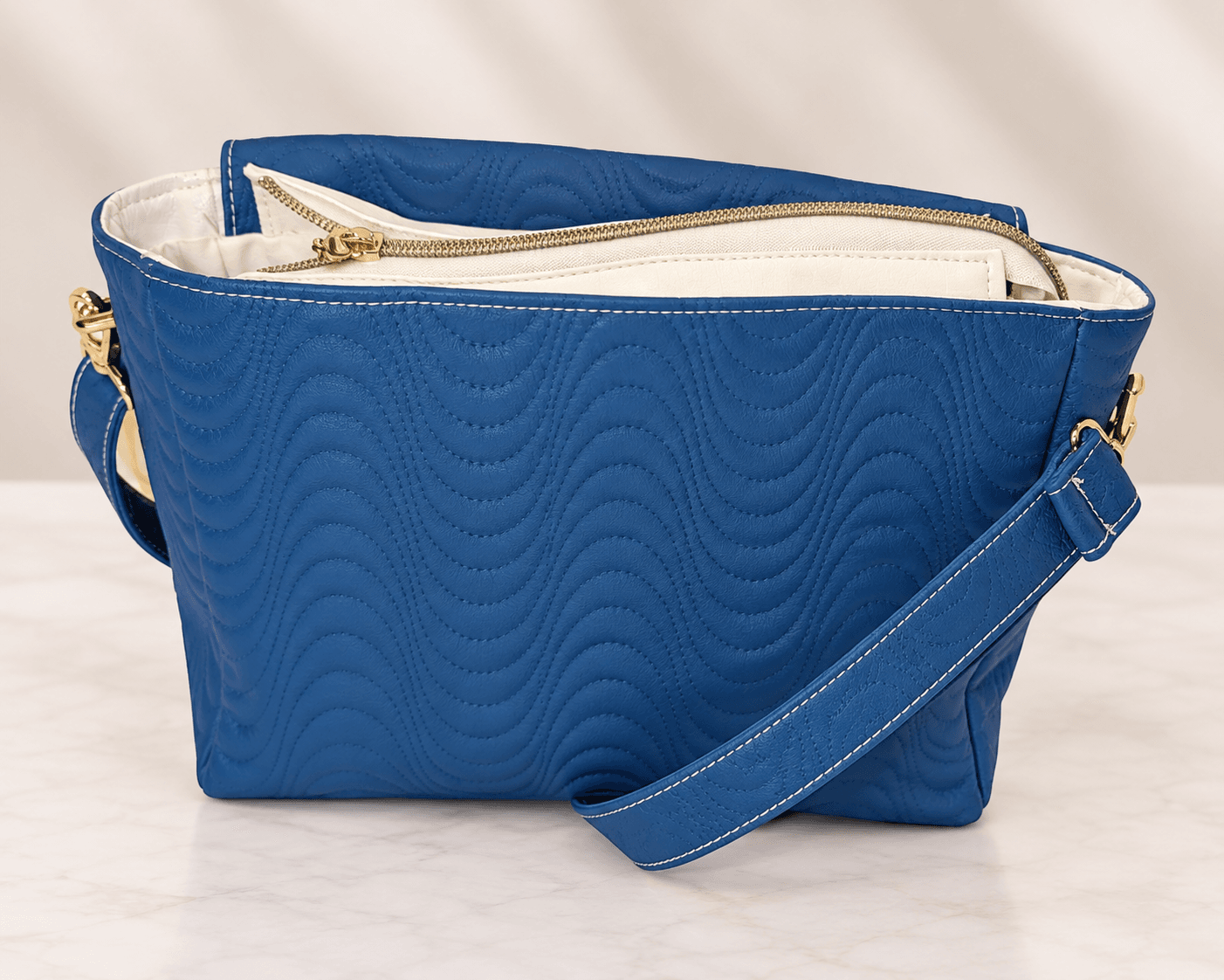 Back view of blue quilted crossbody bag with white zipper detail