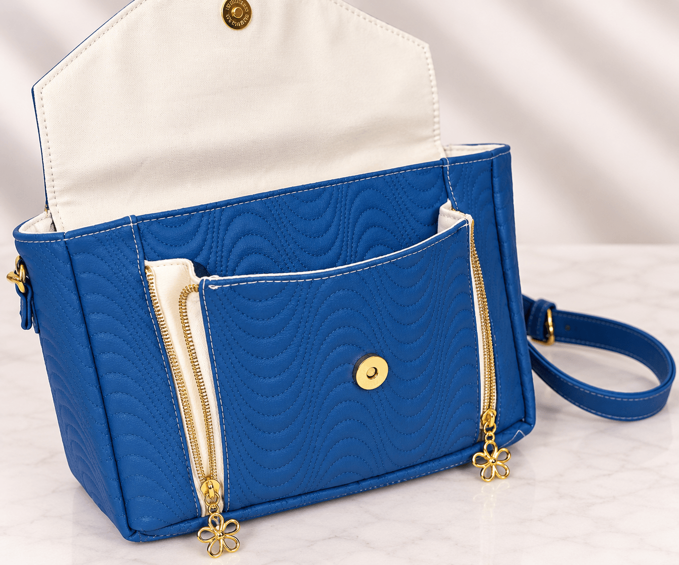 Blue quilted crossbody bag front pocket with magnetic closure and gold zippers