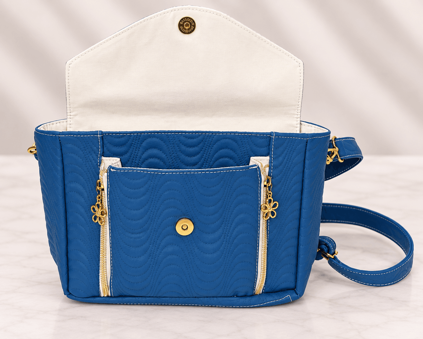 Blue quilted crossbody bag with flap open showing magnetic closure and front pocket