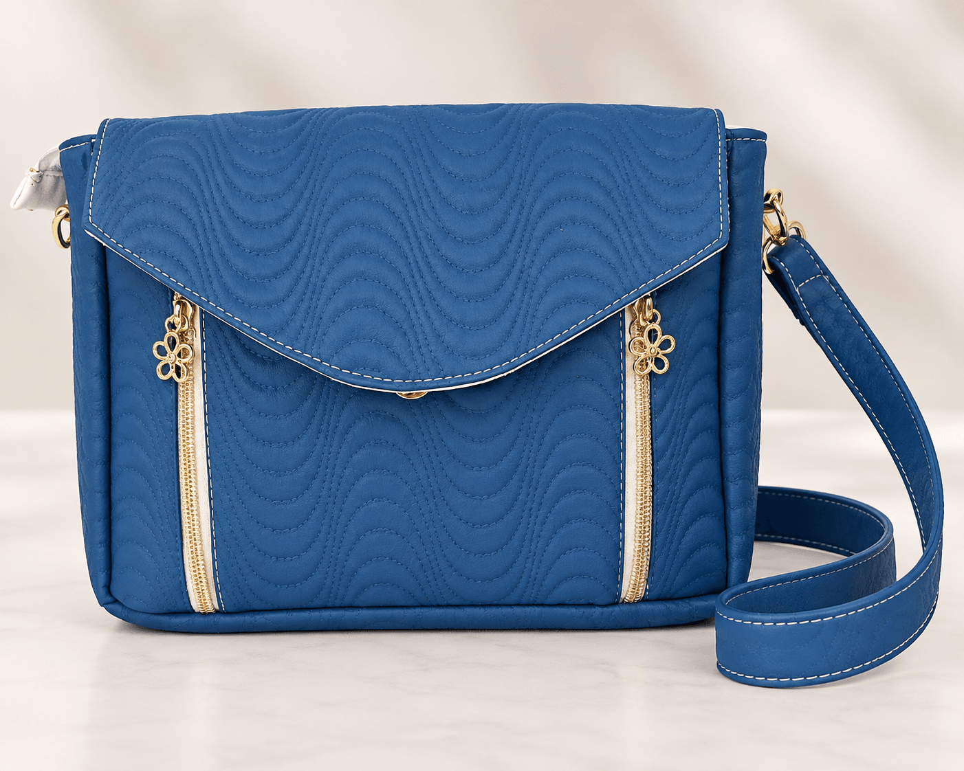 Blue quilted crossbody bag with flap closure and gold zipper accents