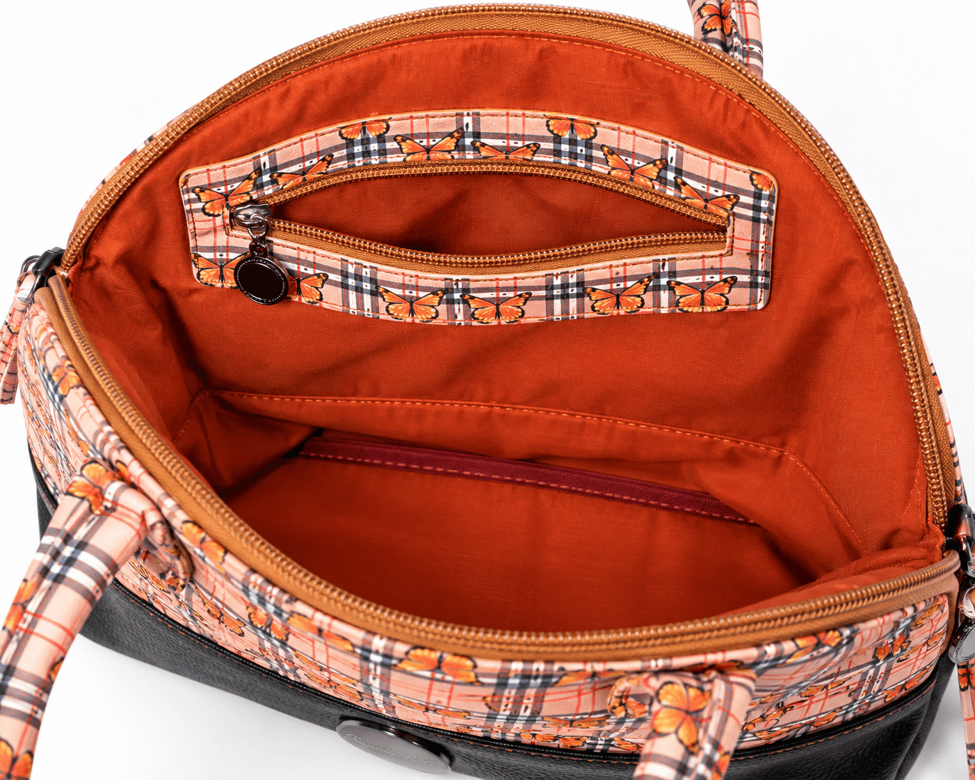 Open butterfly plaid handbag showing rust-colored lining and an interior zippered pocket with matching butterfly plaid fabric.