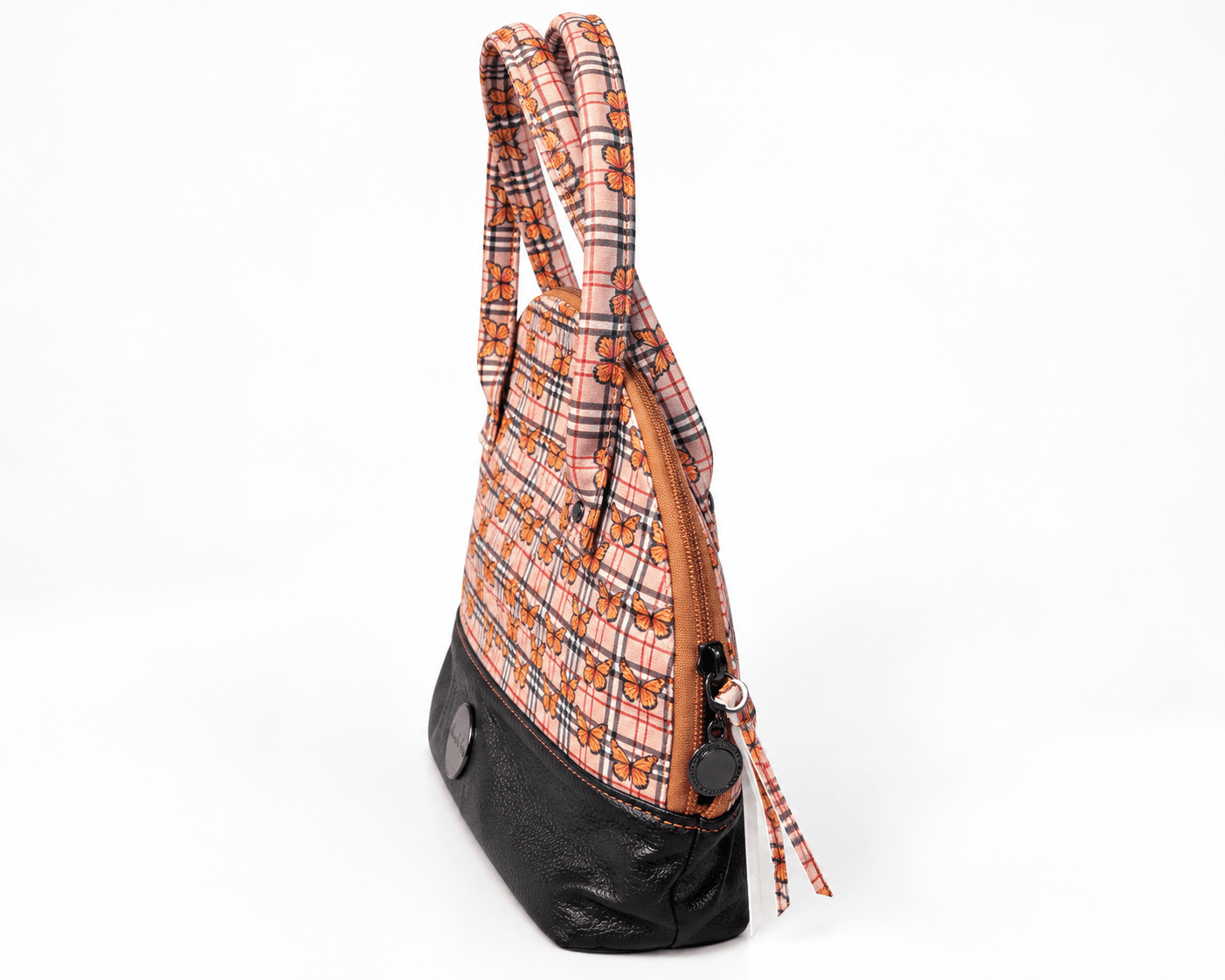 Side profile of orange butterfly plaid handbag showing its compact shape, top zipper and black faux leather base.