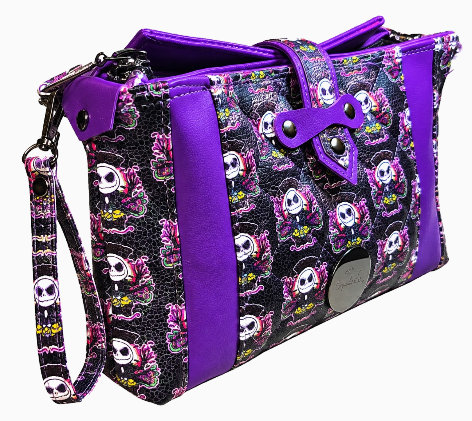 Angled side view of purple and black skull-print wristlet showing its depth, quilted exterior, decorative rivets, and detachable wrist strap.